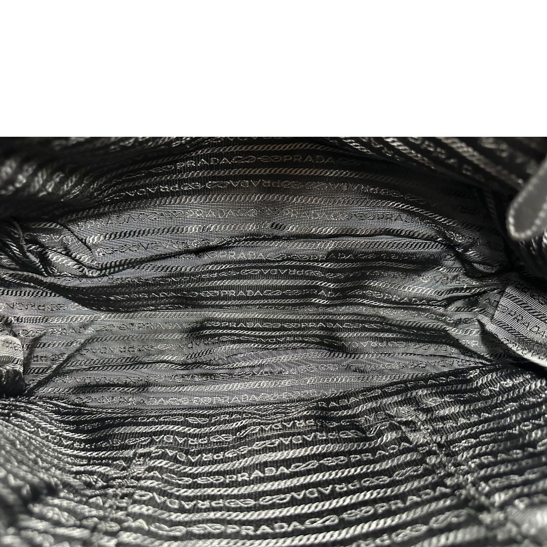 Interno di una Borsa Prada in tessuto nylon goffrato nero con parti metalliche argentate e inserti in pelle tono su tono, munita di una tracolla regolabile e amovibile. Completa di dustbag. Originale, usata, di lusso, in ottime condizioni.