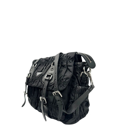 Lato sinistro di una Borsa Prada in tessuto nylon goffrato nero con parti metalliche argentate e inserti in pelle tono su tono, munita di una tracolla regolabile e amovibile. Completa di dustbag. Originale, usata, di lusso, in ottime condizioni.