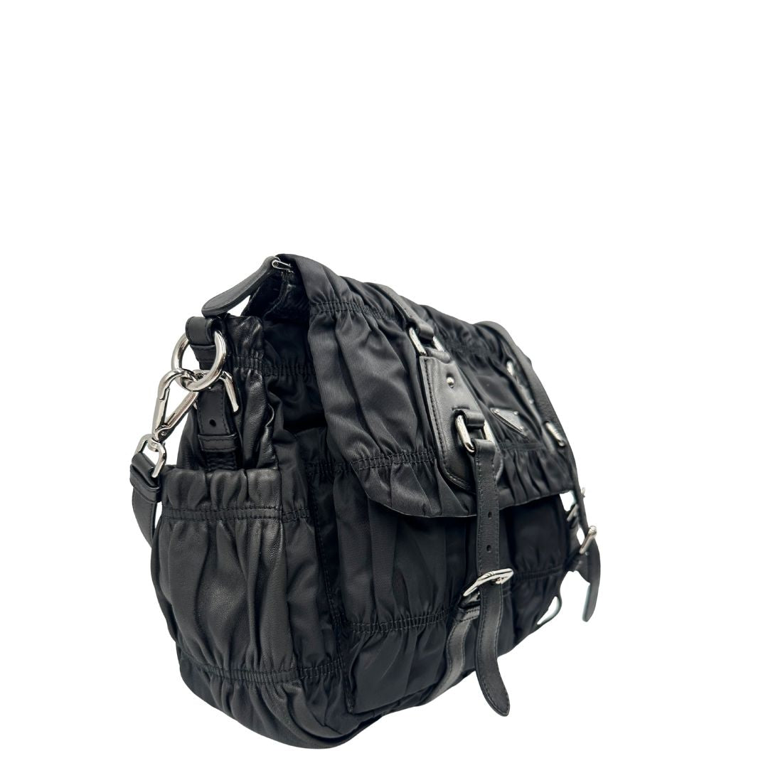 Lato destro di una Borsa Prada in tessuto nylon goffrato nero con parti metalliche argentate e inserti in pelle tono su tono, munita di una tracolla regolabile e amovibile. Completa di dustbag. Originale, usata, di lusso, in ottime condizioni.