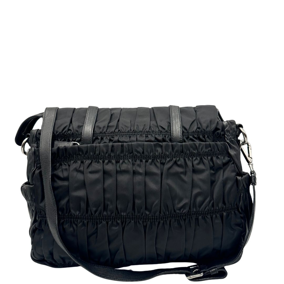 Retro di una Borsa Prada in tessuto nylon goffrato nero con parti metalliche argentate e inserti in pelle tono su tono, munita di una tracolla regolabile e amovibile. Completa di dustbag. Originale, usata, di lusso, in ottime condizioni.