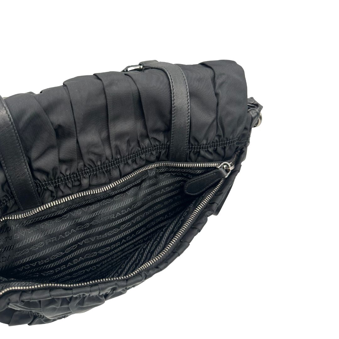 Tasca esterna di una Borsa Prada in tessuto nylon goffrato nero con parti metalliche argentate e inserti in pelle tono su tono, munita di una tracolla regolabile e amovibile. Completa di dustbag. Originale, usata, di lusso, in ottime condizioni.