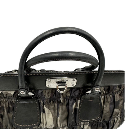 Manici di una Borsa Prada in tessuto nylon goffrato trama camouflage nelle tonlità del verde, finiture in pelle nere e inserti metallici argentati; dotata di doppi manici stondati. Completa di dustbag. Originale, usata, di lusso, in ottime condizioni.