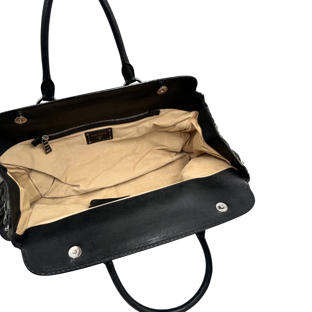 Interno di una Borsa Prada in tessuto nylon goffrato trama camouflage nelle tonlità del verde, finiture in pelle nere e inserti metallici argentati; dotata di doppi manici stondati. Completa di dustbag. Originale, usata, di lusso, in ottime condizioni.