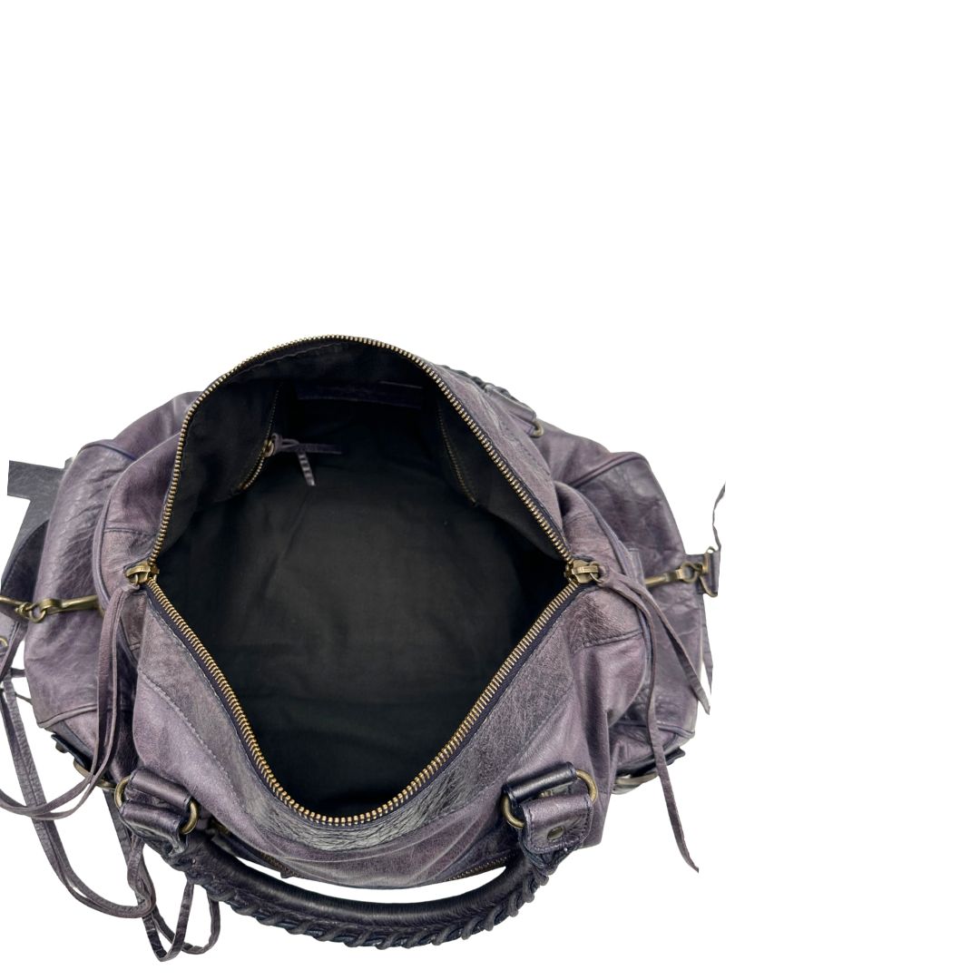 Interno di una Borsa Balenciaga in pelle viola scuro effetto invecchiato con parti metalliche ottone anticato, munita di doppi manici con dettaglio intreccio, e una tracolla amovibile e regolabile con spallaccio. Completa di dustbag. Originale, usata, di lusso, in ottime condizioni.