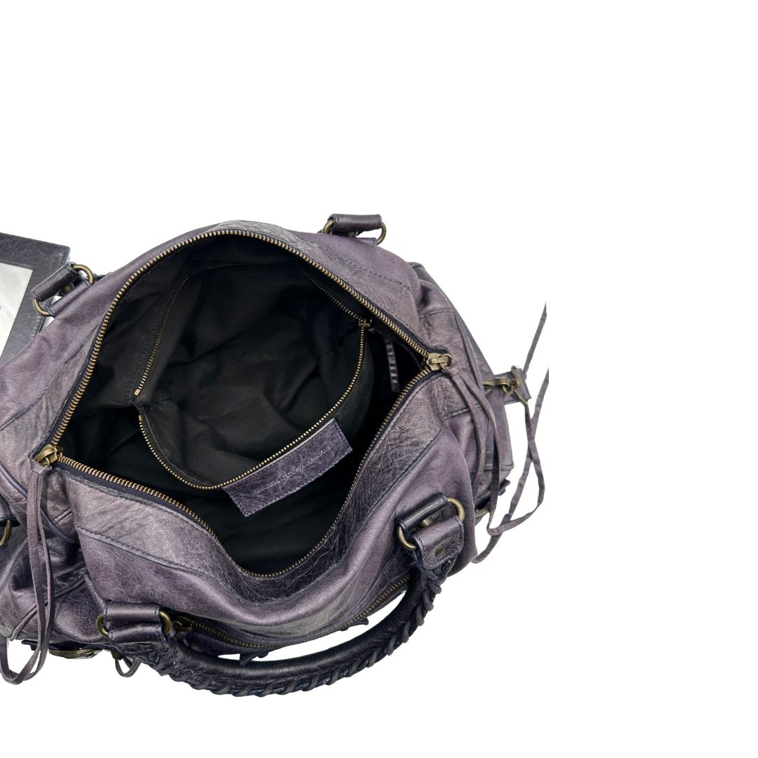 Interno di una Borsa Balenciaga in pelle viola scuro effetto invecchiato con parti metalliche ottone anticato, munita di doppi manici con dettaglio intreccio, e una tracolla amovibile e regolabile con spallaccio. Completa di dustbag. Originale, usata, di lusso, in ottime condizioni.