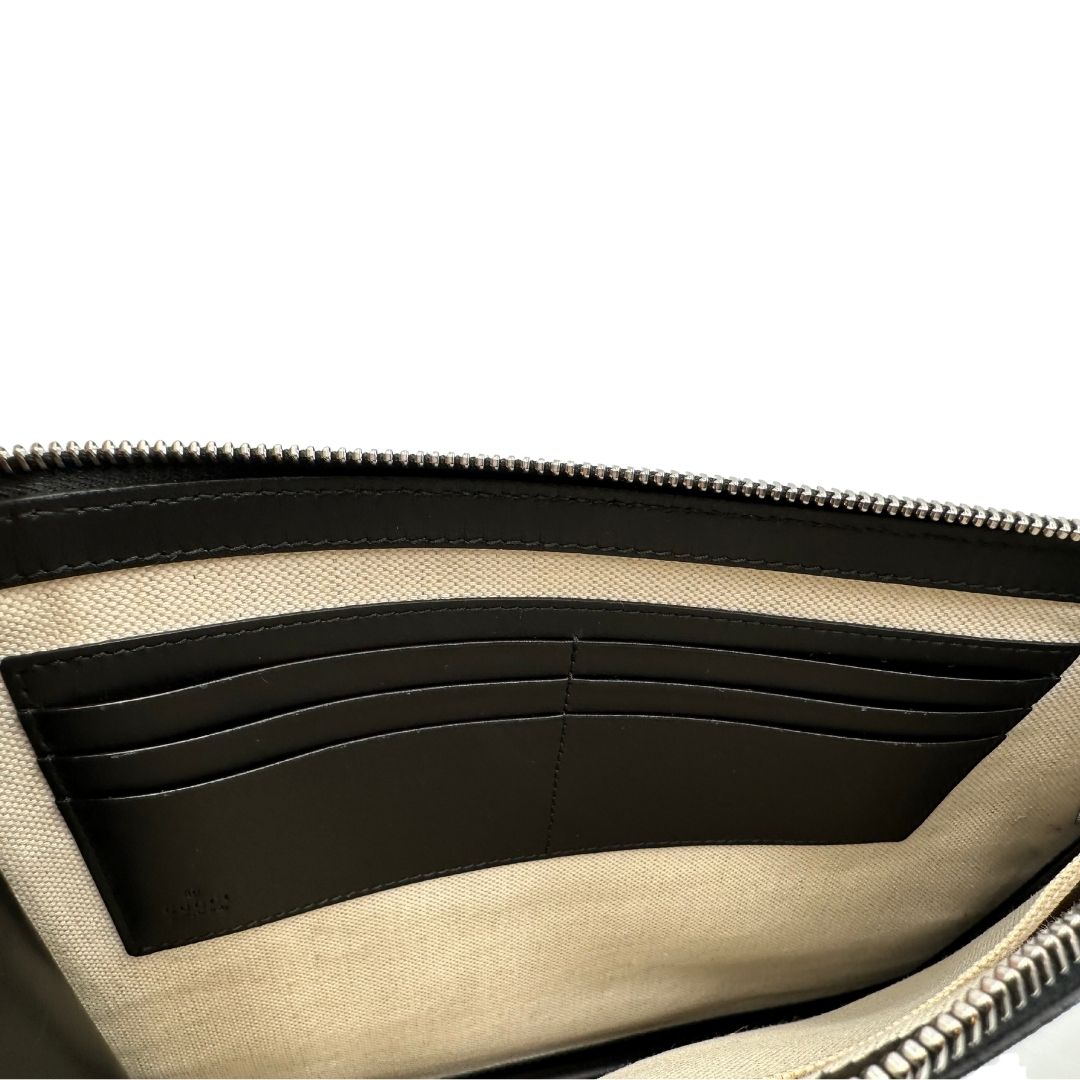 interno  Pochette Gucci in canvas nero con GG grigie antracite e parti metalliche argentate; munita di un polsino e impreziosita da stampa lupo sul front, di lusso,originale, ottime condizioni. 
