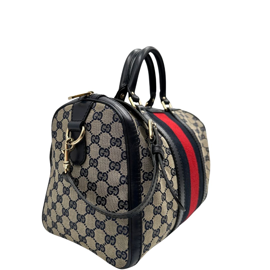 lato  Borsa Gucci in tessuto blu GG con finiture in pelle tono su tono, parti metalliche dorate e striscia Web blu e rossa; munita di doppi manici stondati e una tracolla amovibile e regolabile. Completa di dustbag, di lusso, originale, ottime condizioni, usata. 