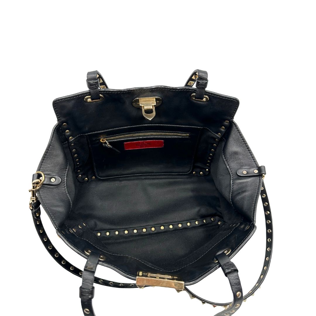 Interno di una Borsa Valentino Garavani in pelle nera con parti metalliche dorate; impreziosita da borchie piramidali e munita di doppi manici e una tracolla amovibile. Completa di dustbag e cartellino. Originale, usata, di lusso, in ottime condizioni.