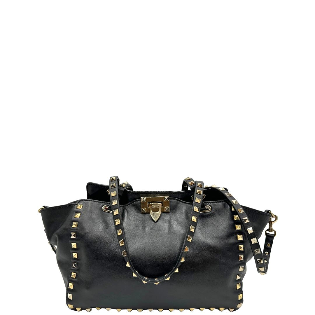 Front di una Borsa Valentino Garavani in pelle nera con parti metalliche dorate; impreziosita da borchie piramidali e munita di doppi manici e una tracolla amovibile. Completa di dustbag e cartellino. Originale, usata, di lusso, in ottime condizioni.