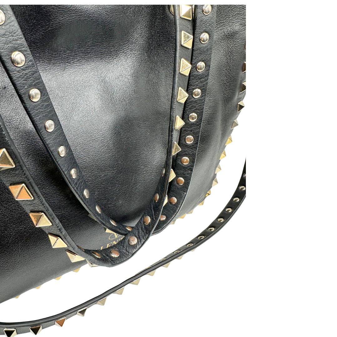 Manici di una Borsa Valentino Garavani in pelle nera con parti metalliche dorate; impreziosita da borchie piramidali e munita di doppi manici e una tracolla amovibile. Completa di dustbag e cartellino. Originale, usata, di lusso, in ottime condizioni.