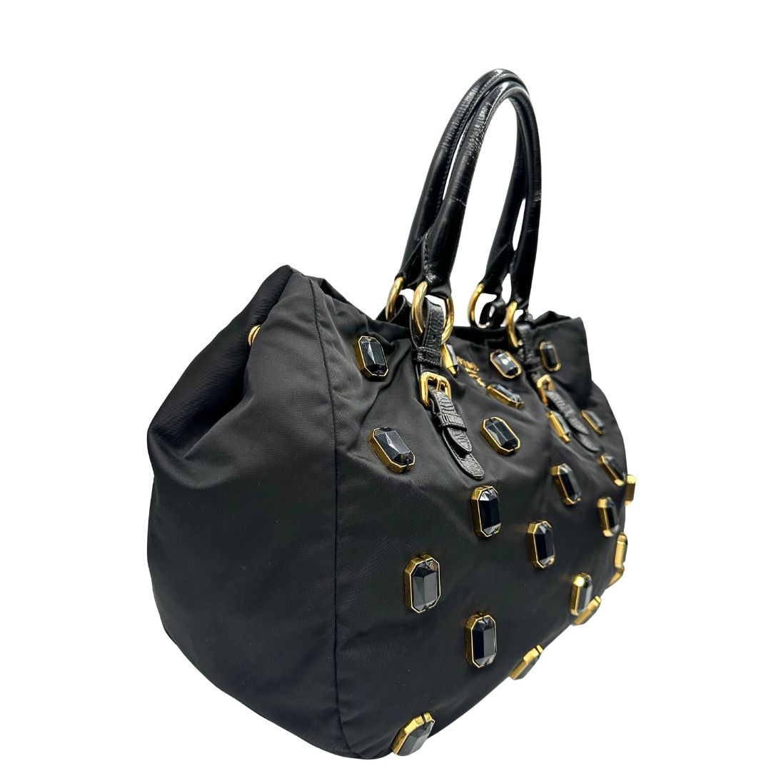 lato  Borsa Prada in nylon nero con parti metalliche dorate e manici in pelle lucida; impreziosita da pietre su tutta la superficie del front; munita di doppi manici stondati, di lusso, originale, ottime condizioni, usata. 