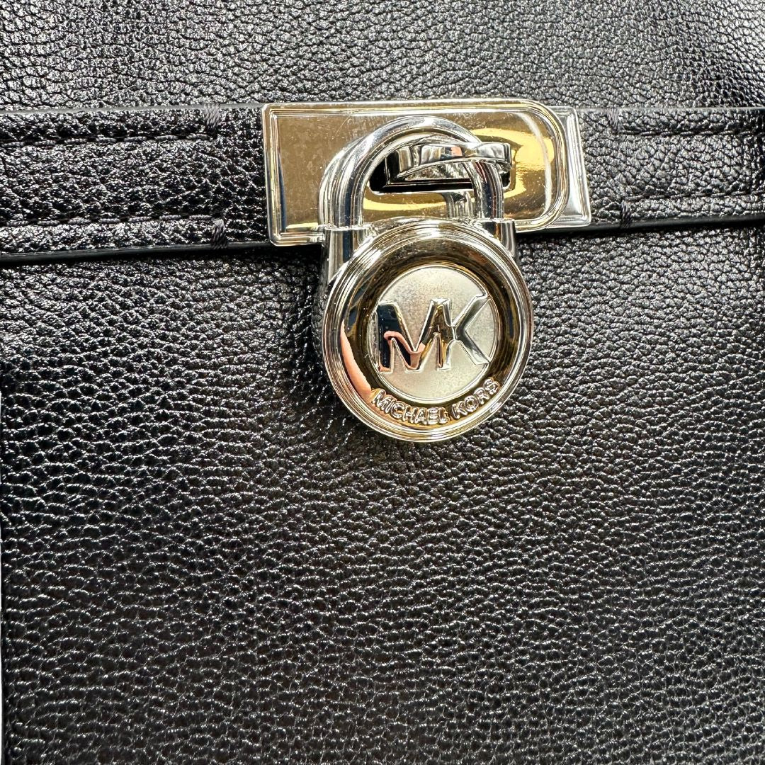 Parte metallica di una borsa Michael Kors in pelle nera con parti metalliche argentate; munita di doppi manici. Completa di dustbag. Indossabile a spalla.