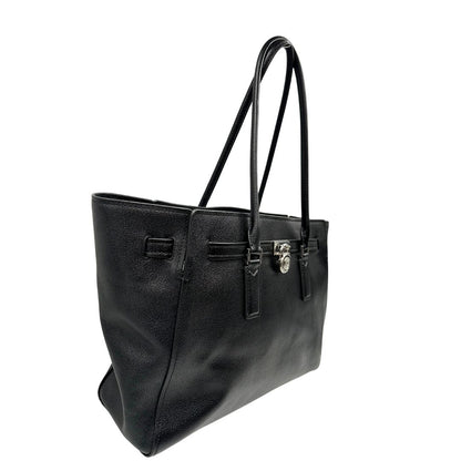 Laterale sinistro di una borsa Michael Kors in pelle nera con parti metalliche argentate; munita di doppi manici. Completa di dustbag. Indossabile a spalla.