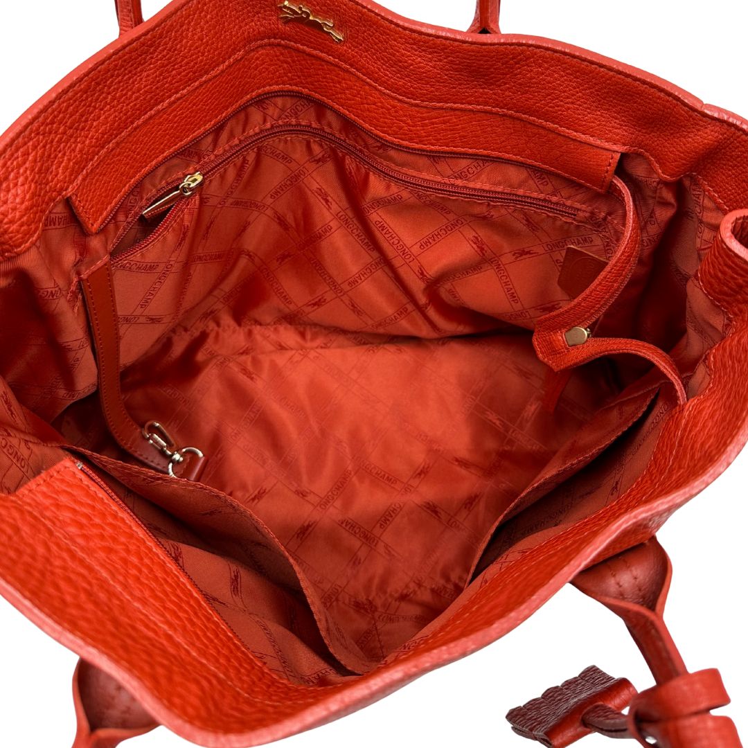 interno Borsa Longchamp in pelle martellata rosso corallo con parti metalliche dorate; munita di doppi manici, indossabile a spalla. Completa di dustbag, di lusso, originale, ottime condizioni. 