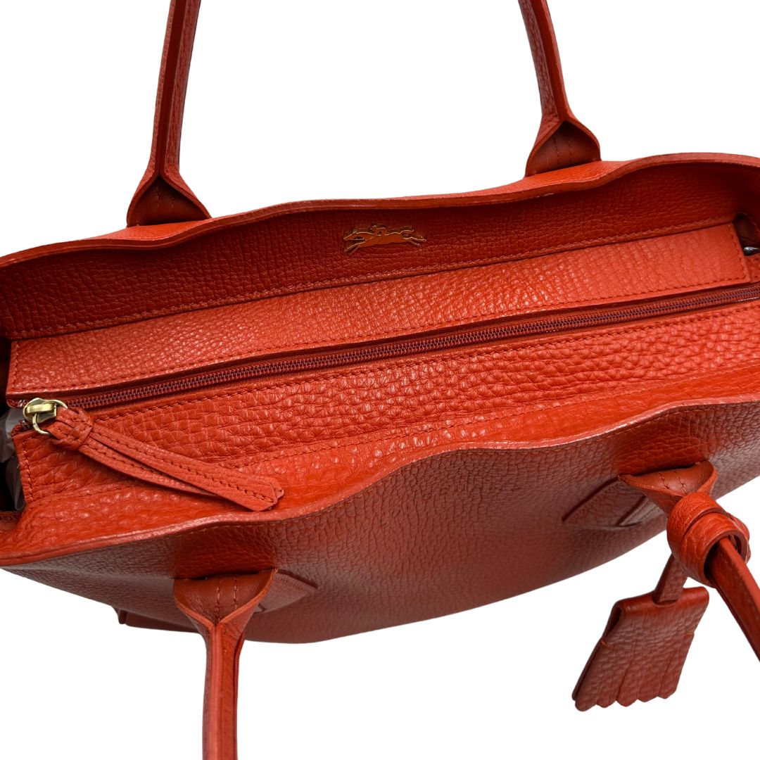 cerniera Borsa Longchamp in pelle martellata rosso corallo con parti metalliche dorate; munita di doppi manici, indossabile a spalla. Completa di dustbag, di lusso, originale, ottime condizioni. 