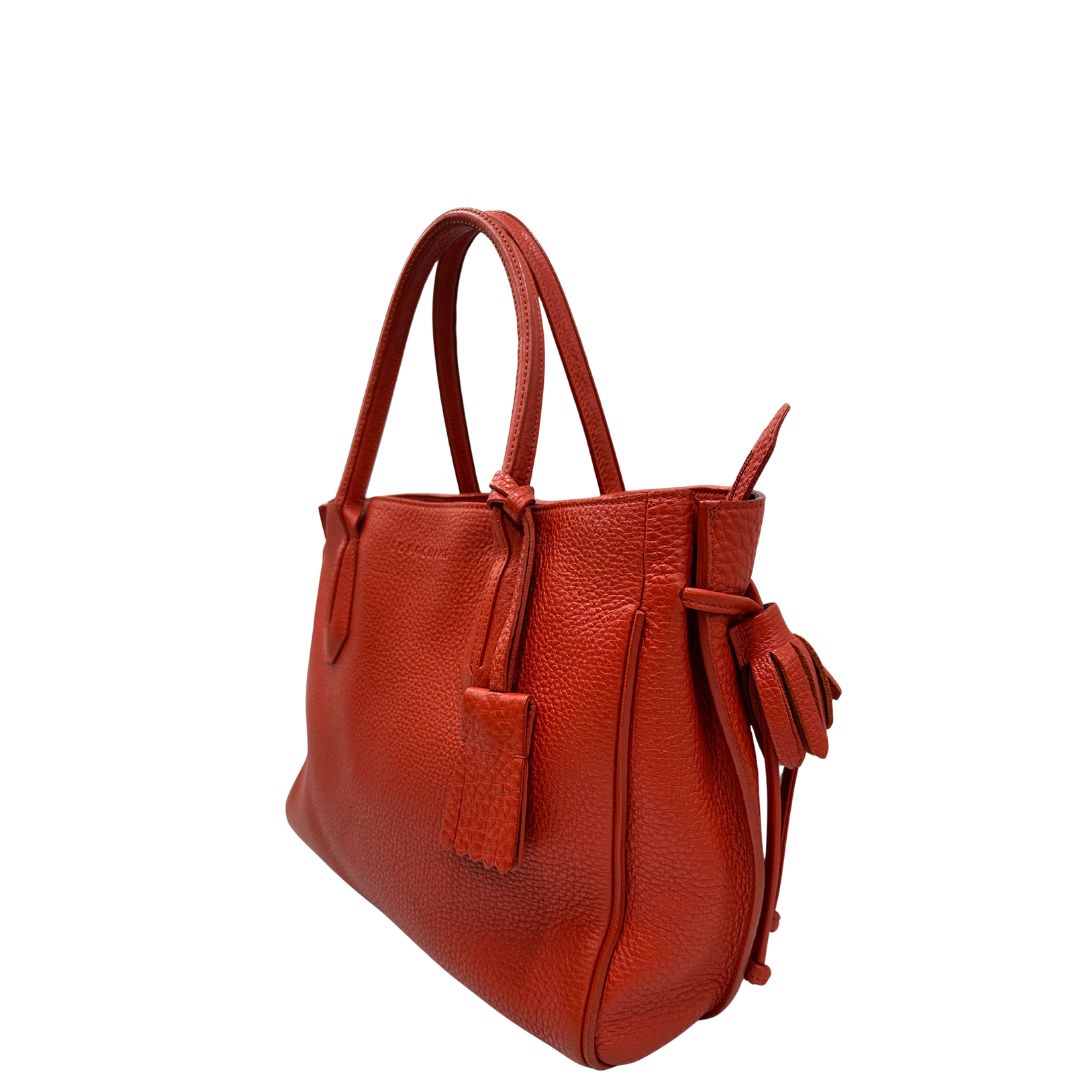 lato Borsa Longchamp in pelle martellata rosso corallo con parti metalliche dorate; munita di doppi manici, indossabile a spalla. Completa di dustbag, di lusso, originale, ottime condizioni. 