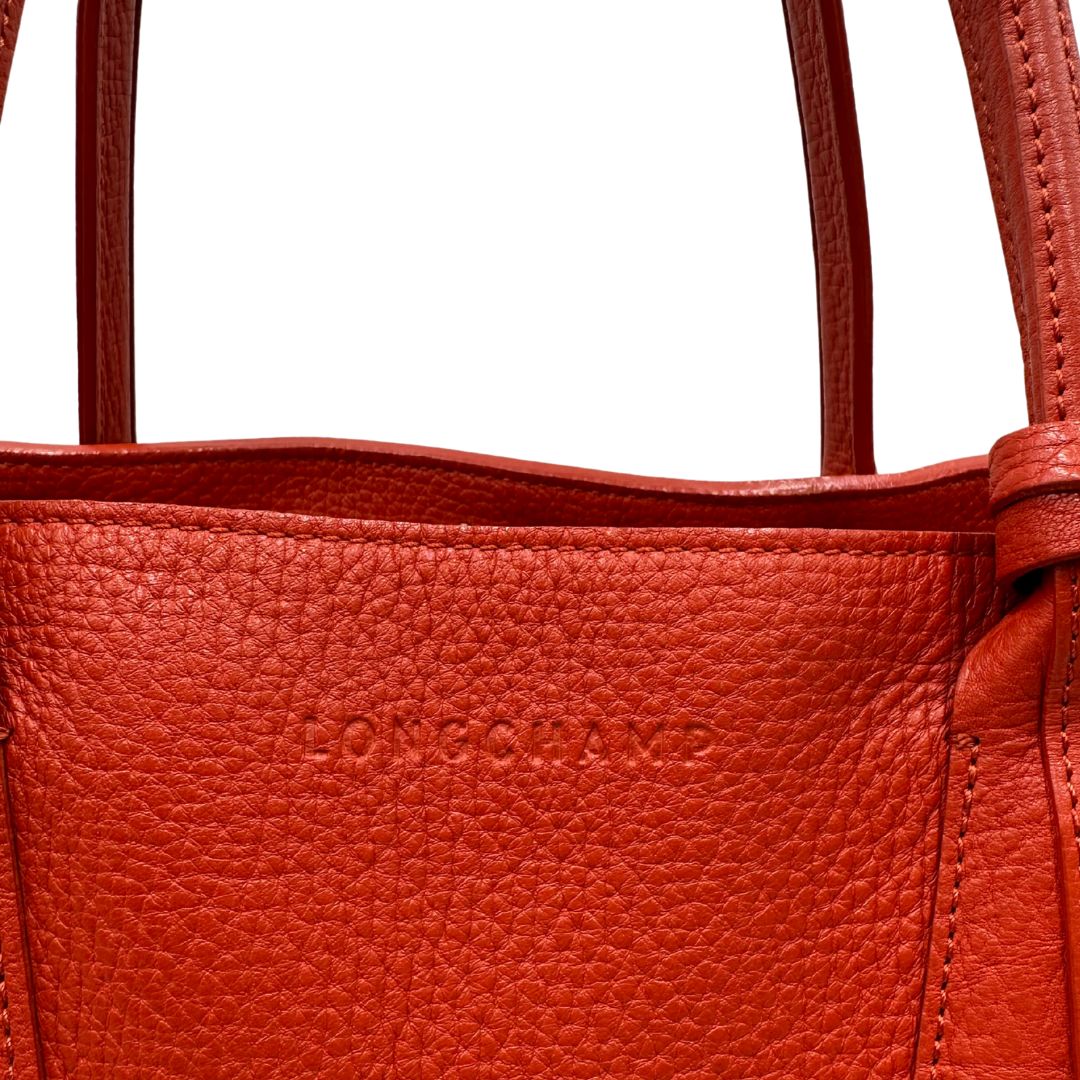 logo Borsa Longchamp in pelle martellata rosso corallo con parti metalliche dorate; munita di doppi manici, indossabile a spalla. Completa di dustbag, di lusso, originale, ottime condizioni.