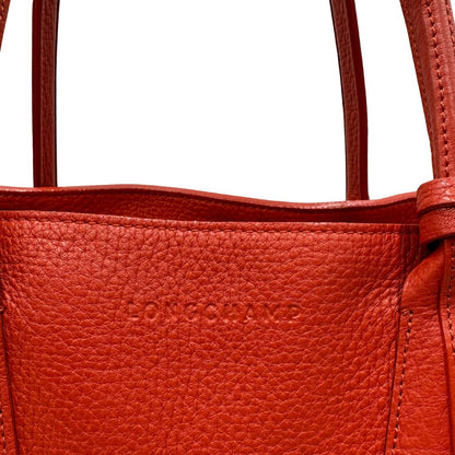 logo Borsa Longchamp in pelle martellata rosso corallo con parti metalliche dorate; munita di doppi manici, indossabile a spalla. Completa di dustbag, di lusso, originale, ottime condizioni.