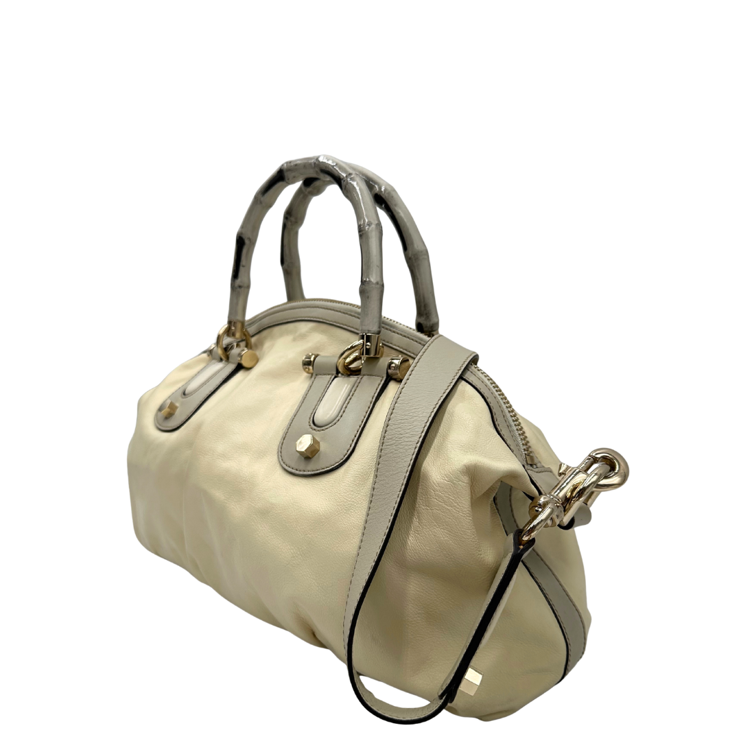 Lato sinistro di una Borsa Gucci in pelle bianco panna con metalleria in oro dorato e inserti in pelle avorio, munita di doppi manici in bamboo e tracolla amovibile. Completa di dutsbag. Originale, usata, di lusso, in ottime condizioni.