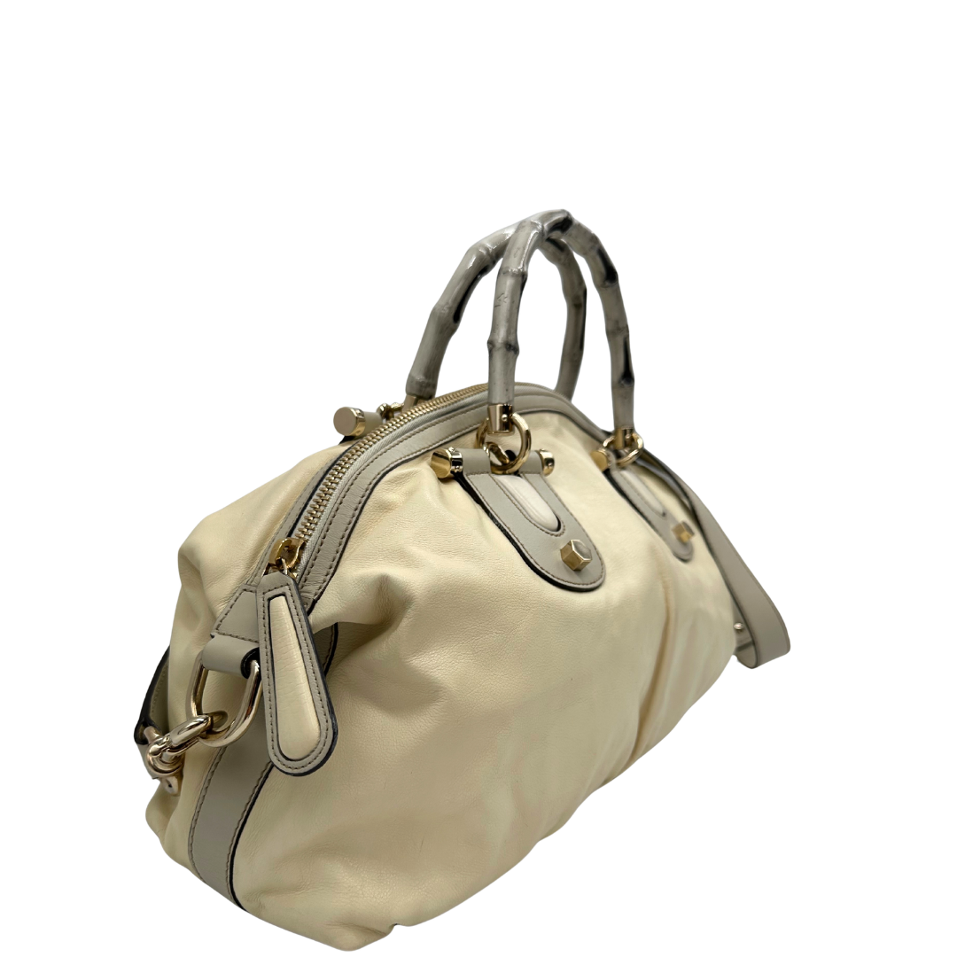 Lato destro di una Borsa Gucci in pelle bianco panna con metalleria in oro dorato e inserti in pelle avorio, munita di doppi manici in bamboo e tracolla amovibile. Completa di dutsbag. Originale, usata, di lusso, in ottime condizioni.