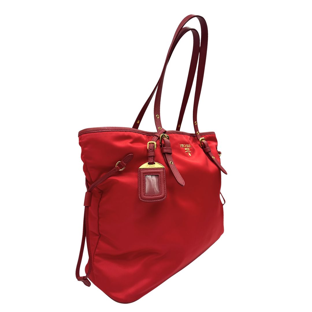 Laterale sinistro di una borsa Prada in nylon rosso e finiture in pelle saffiano tono su tono, usata, originale, second hand, in ottime condizioni.