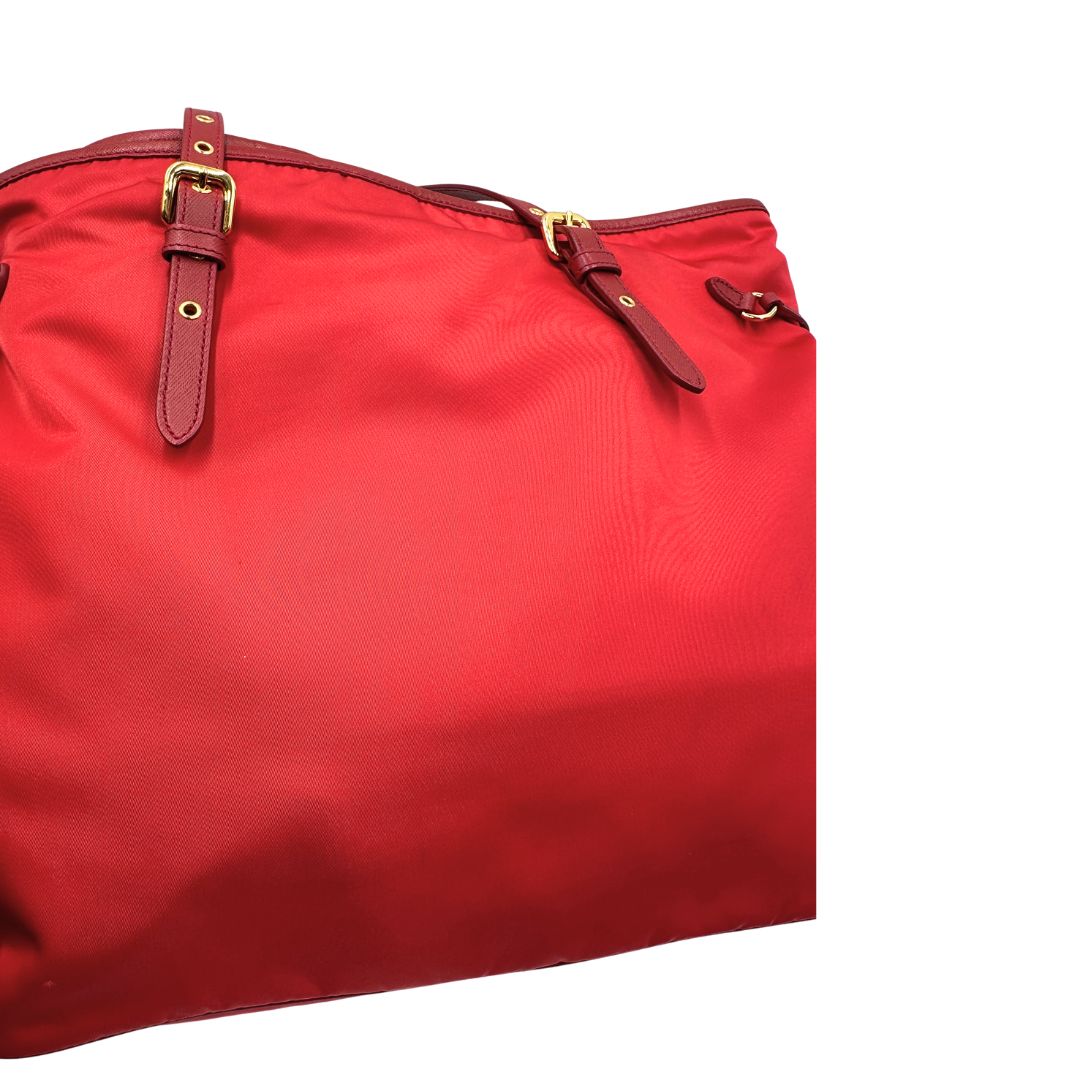 Segni sul tessuto di una borsa Prada in nylon rosso e finiture in pelle saffiano tono su tono, usata, originale, second hand, in ottime condizioni.