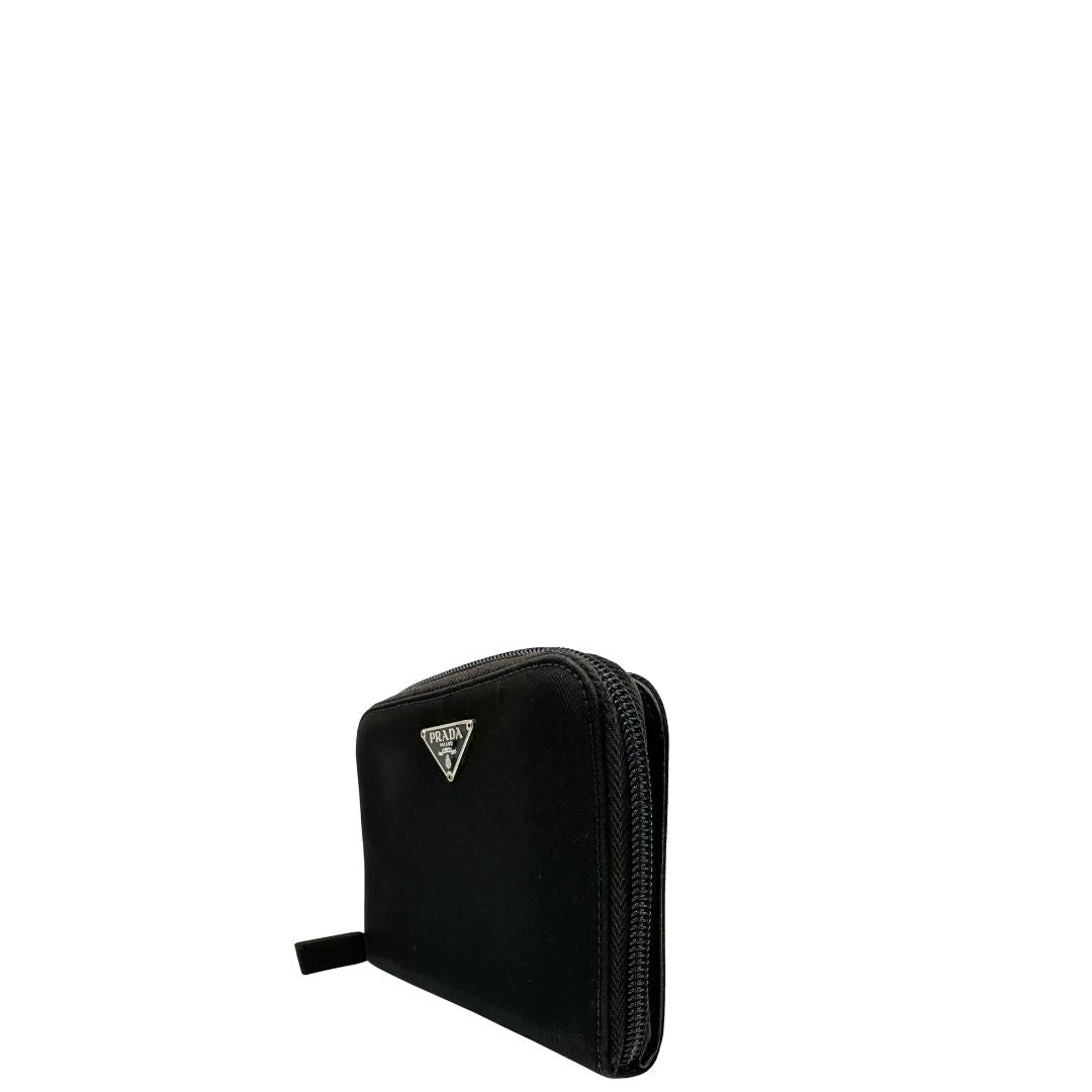 Lato sinistro, Portafoglio Prada in nylon nero con chiusura a zip e l'iconico logo triangolare in metallo. Originale, usato, di lusso, in ottime condizioni.
