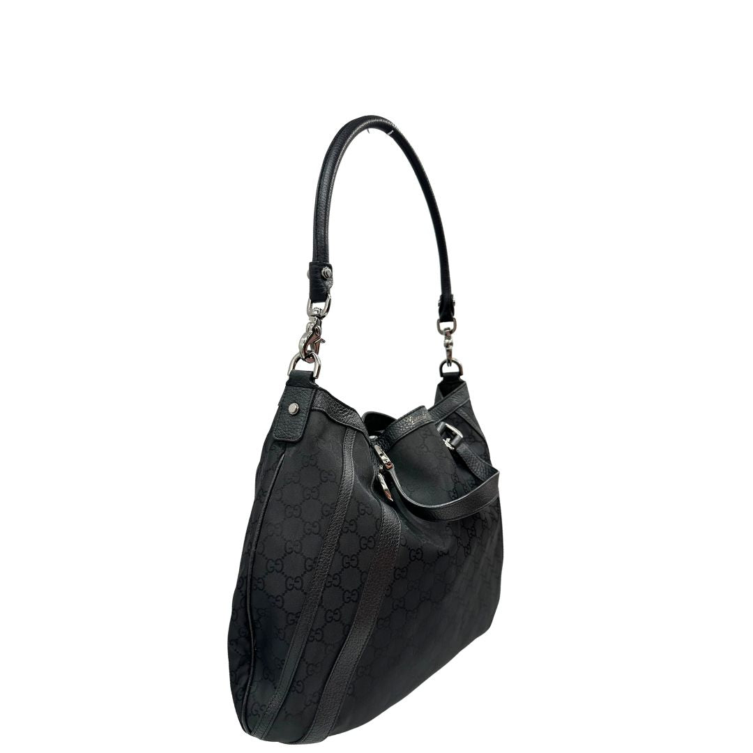 Lato destro, Borsa Gucci in tessuto nero trama GG, con parti metalliche argentate, indossabile a mano o a spalla. Originale, usata, di lusso, in ottime condizioni.