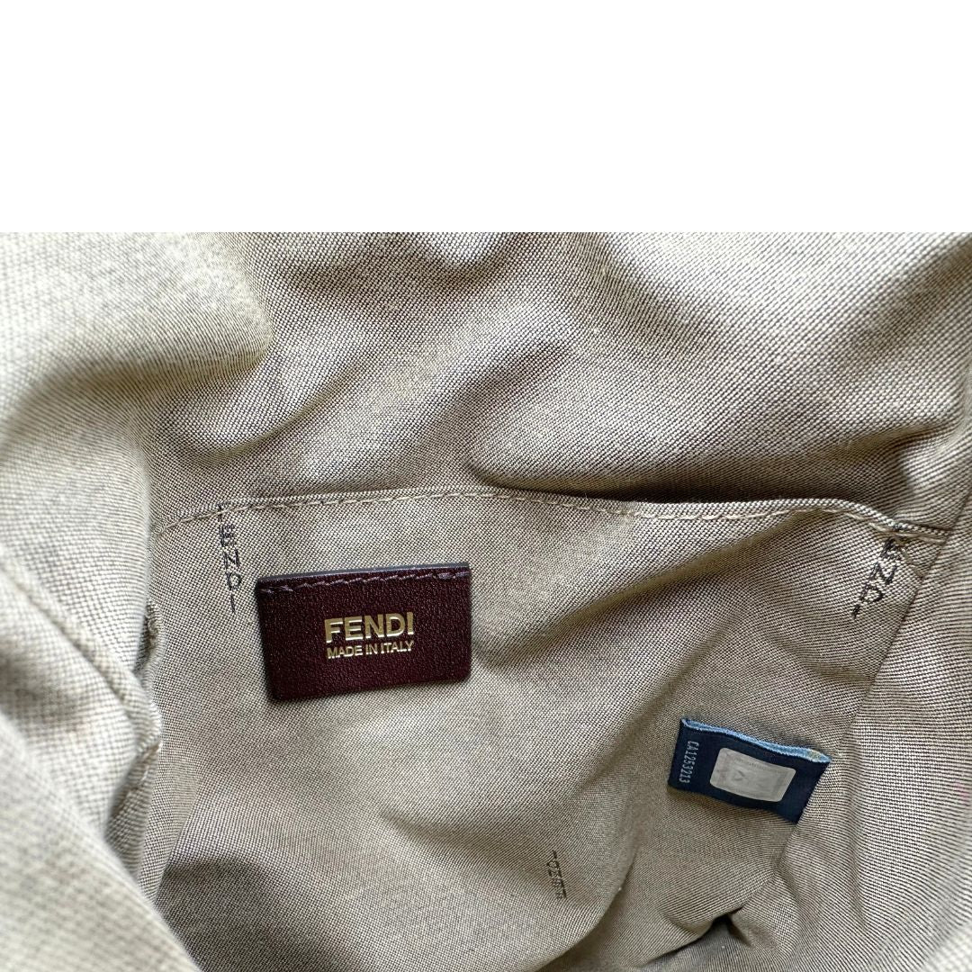 Interno di una tracolla Fendi fucsia in trama Zucchino con finiture in pelle color biscotto e piccolo charm logato come tirante, usata, originale, second hand, in ottime condizioni.