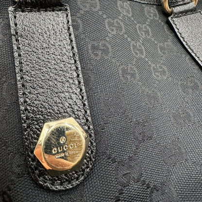 Dettaglio in metallo di una borsa a spalla Gucci in tessuto nero trama GG, con parti metalliche dorate, usata, originale, second hand, in ottime condizioni.