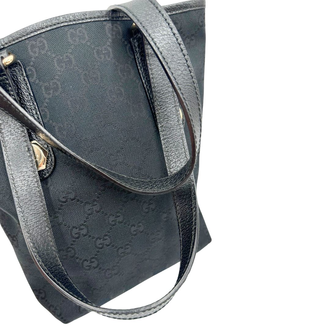 Manici di una borsa a spalla Gucci in tessuto nero trama GG, con parti metalliche dorate, usata, originale, second hand, in ottime condizioni.