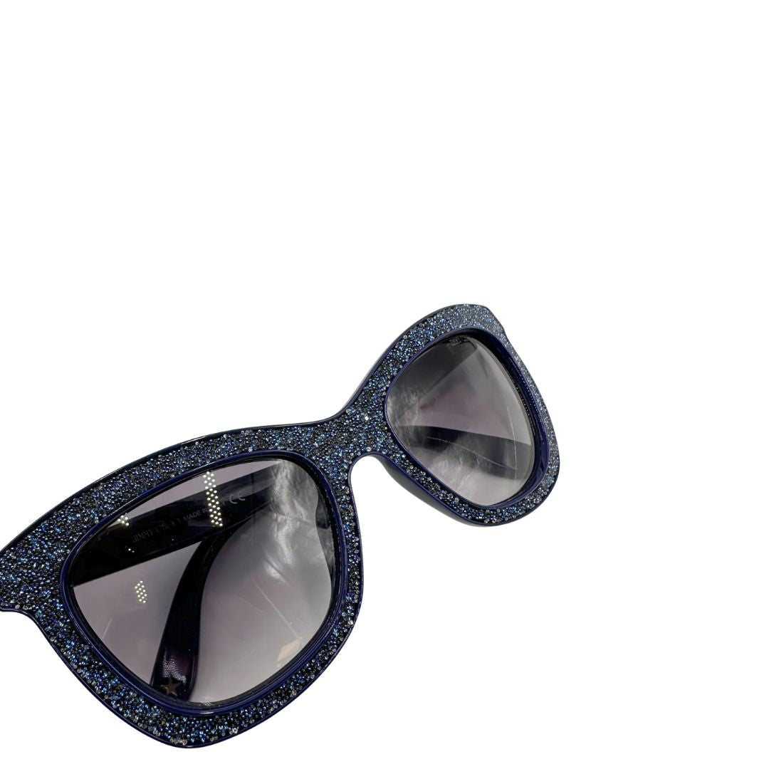 Occhiali da sole Jimmy Choo nella variante colore FIALF Blue Grey con una montatura in acetato blu impreziosita da un effetto glitterato e lenti grigio sfumato. Originale, usati, di lusso, in ottime condizioni.