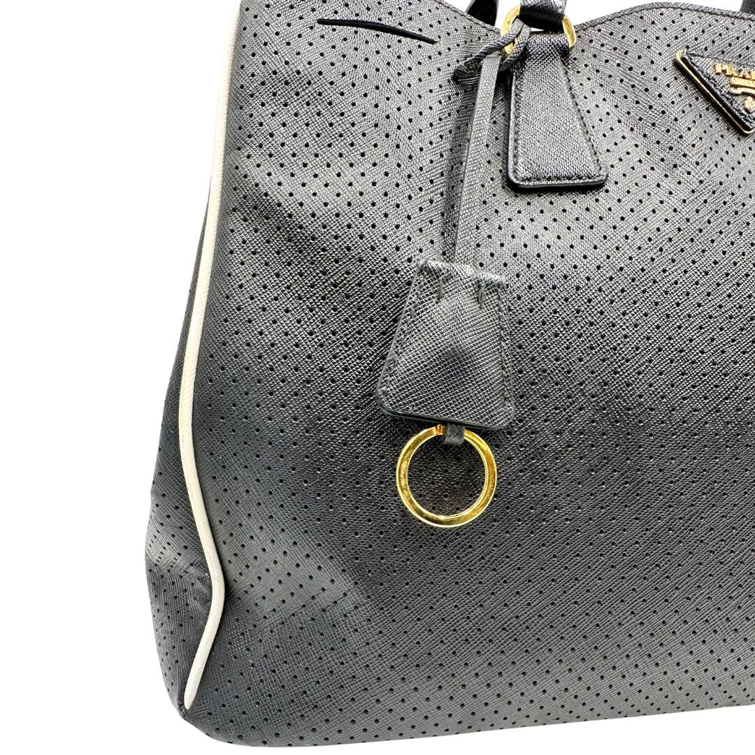 lato Borsa Prada Galleria in pelle traforata nera con eleganti profili bianchi, di lusso, originale, ottime condizioni, usata. 