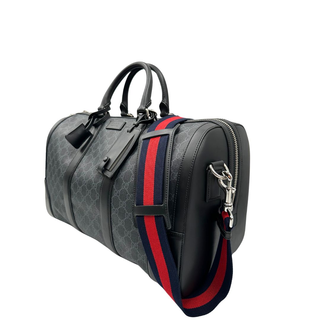 Lato sinistro, Borsone da viaggio Gucci Savoy misura piccola in canvas GG supreme nero con parti metalliche argentate, da portare a mano oppure a spalla. Originale, usato, di lusso, in ottime condizioni.