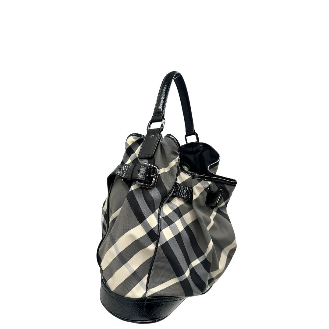 Laterale sinistro di una borsa Burberry in poliammide e acrilico trama tartan, con finiture nere lucide, usata, originale, second hand, in ottime condizioni.