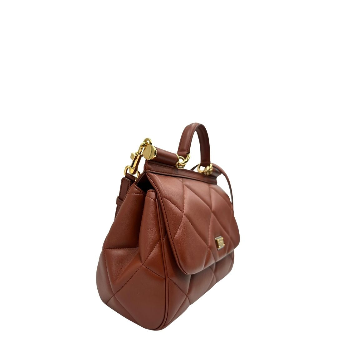 Laterale sinistro di una borsa D&G in pelle trapuntata color terracotta, e hardware dorato, indossabile a mano oppure a tracolla, usata, originale, second hand, in ottime condizioni.