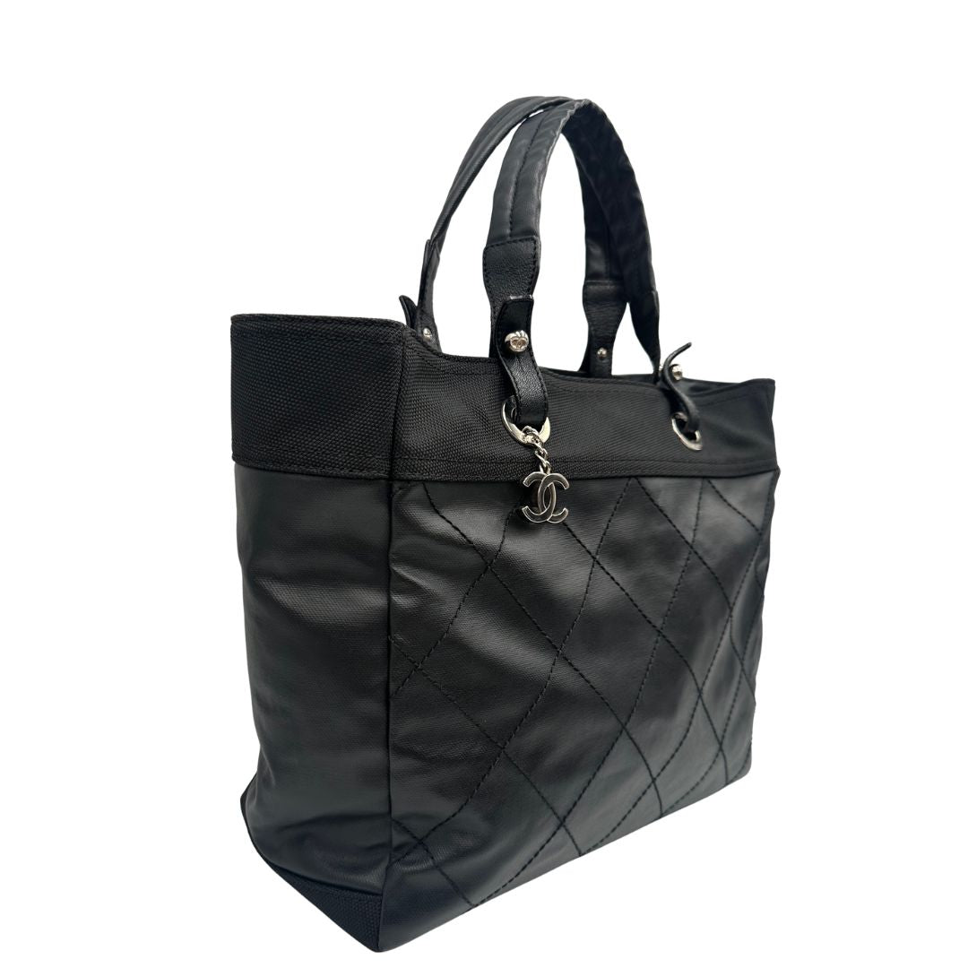 lato Borsa Chanel in pelle nera, caratterizzata da linee morbide ed eleganti. Dotata di doppi manici e charm CC iconico con finiture argentate, di lusso, originale, ottime condizioni, usata. 