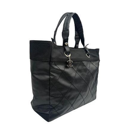 lato Borsa Chanel in pelle nera, caratterizzata da linee morbide ed eleganti. Dotata di doppi manici e charm CC iconico con finiture argentate, di lusso, originale, ottime condizioni, usata. 