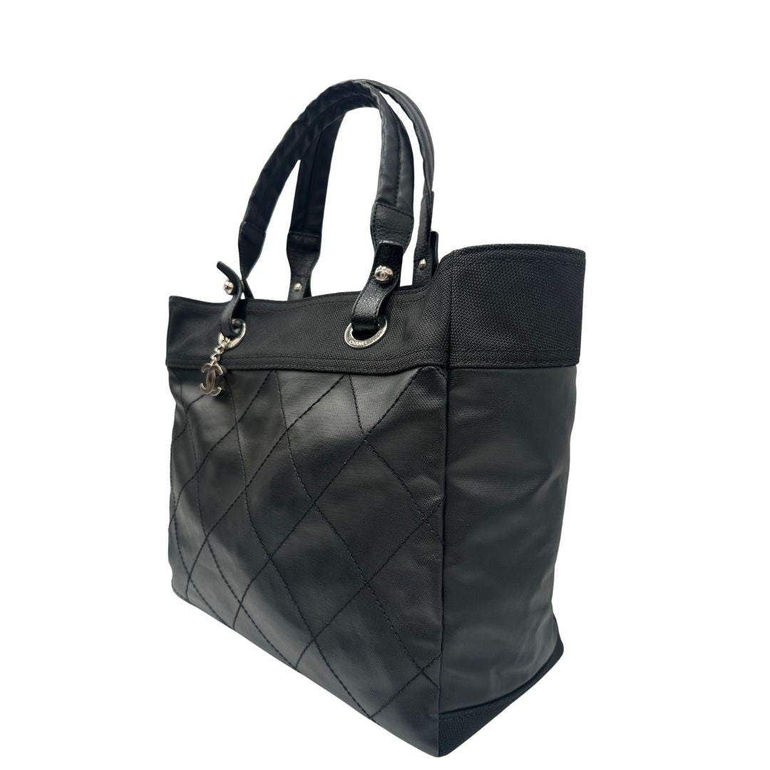 lato Borsa Chanel in pelle nera, caratterizzata da linee morbide ed eleganti. Dotata di doppi manici e charm CC iconico con finiture argentate, di lusso, originale, ottime condizioni, usata. 