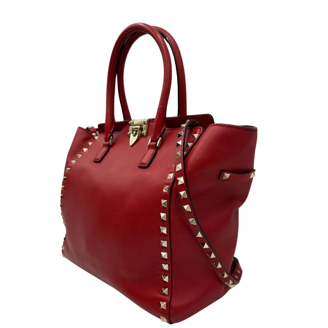 lato Borsa V. G. in pelle rossa impreziosita da borchie piramidali dorate, di lusso, originale, ottime condizioni, usata. 