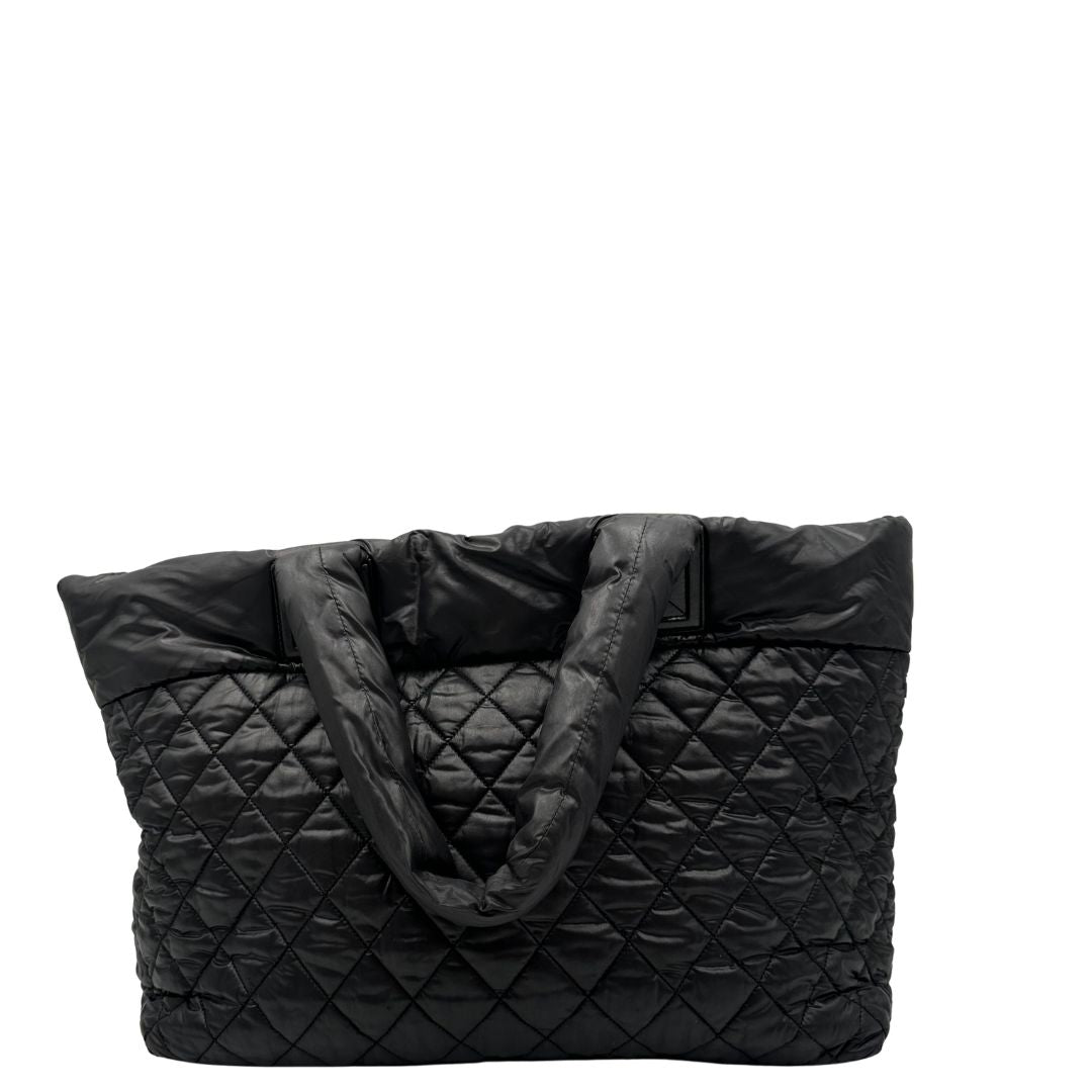 retro Chanel in nylon trapuntato nero, caratterizzata da design morbido e leggero con iconico motivo matelassé. Dotata di doppi manici imbottiti, tasca frontale con zip e dettagli argentati, di lusso, originale, ottime condizioni. 