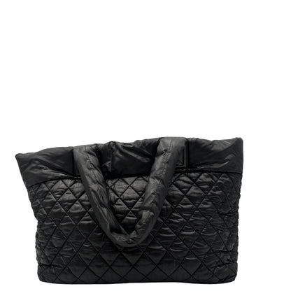retro Chanel in nylon trapuntato nero, caratterizzata da design morbido e leggero con iconico motivo matelassé. Dotata di doppi manici imbottiti, tasca frontale con zip e dettagli argentati, di lusso, originale, ottime condizioni. 