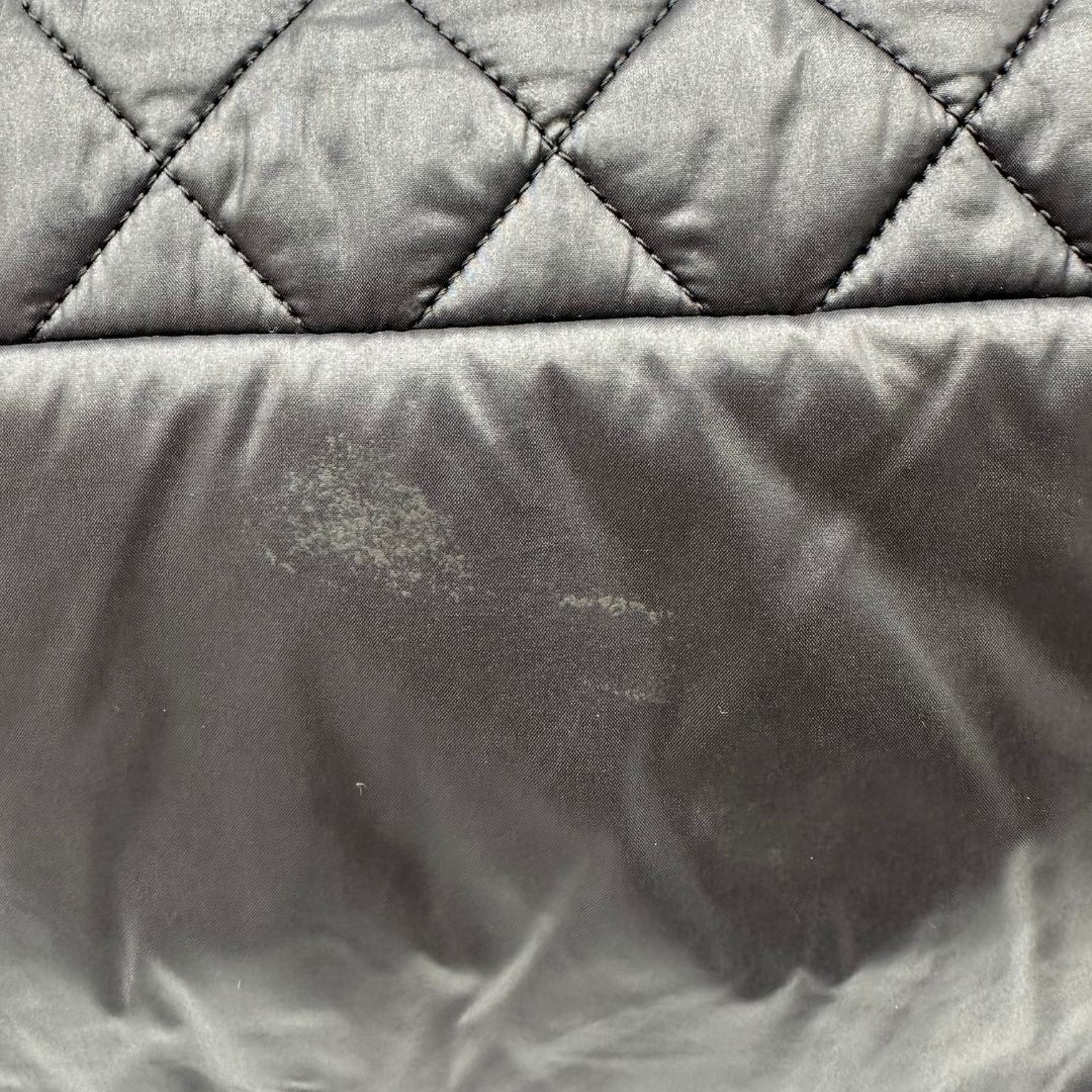 Chanel in nylon trapuntato nero, caratterizzata da design morbido e leggero con iconico motivo matelassé. Dotata di doppi manici imbottiti, tasca frontale con zip e dettagli argentati, di lusso, originale, ottime condizioni.