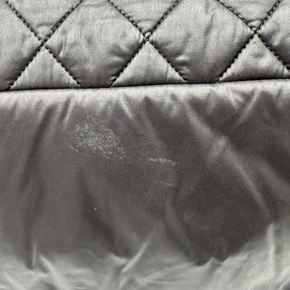 Chanel in nylon trapuntato nero, caratterizzata da design morbido e leggero con iconico motivo matelassé. Dotata di doppi manici imbottiti, tasca frontale con zip e dettagli argentati, di lusso, originale, ottime condizioni.