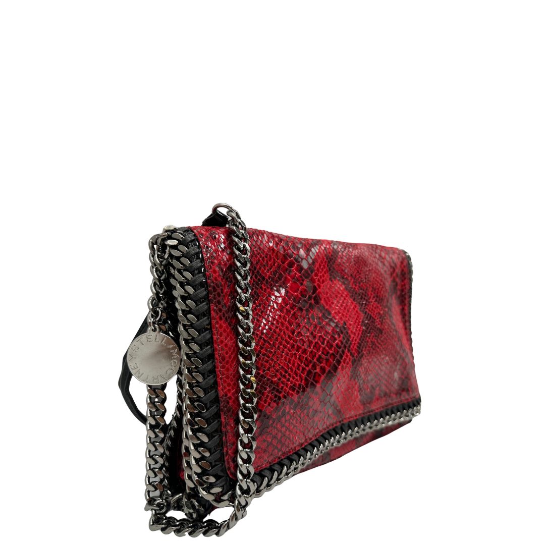 Laterale, Borsa Stella McCartney, modello compatto e grintoso, realizzata in ecopelle effetto pitone rosso lucido e impreziosita da dettagli con catena metallica nera lungo i bordi. Indossabile a tracolla. Originale, usata, di lusso, in ottime condizioni.