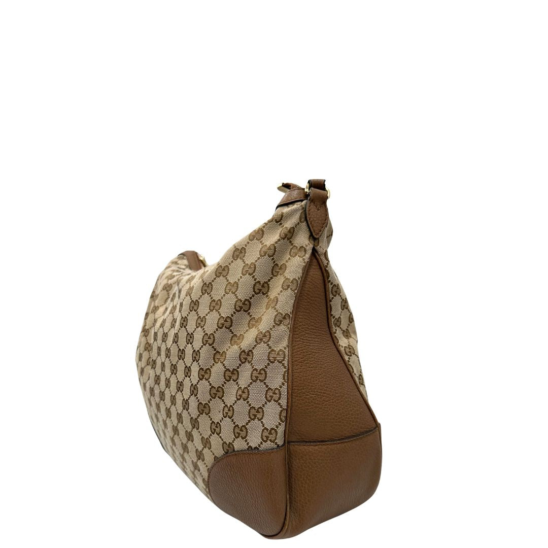 Laterale, Borsa Gucci GG in tessuto e pelle marrone; munita di un manico singolo, indossabile a spalla. Originale, usata, di lusso, in buone condizioni.