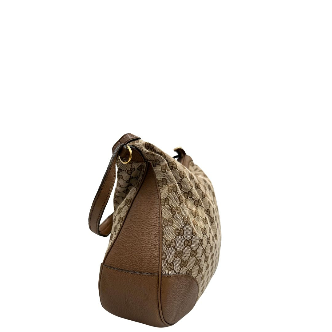 Laterale, Borsa Gucci GG in tessuto e pelle marrone; munita di un manico singolo, indossabile a spalla. Originale, usata, di lusso, in buone condizioni.