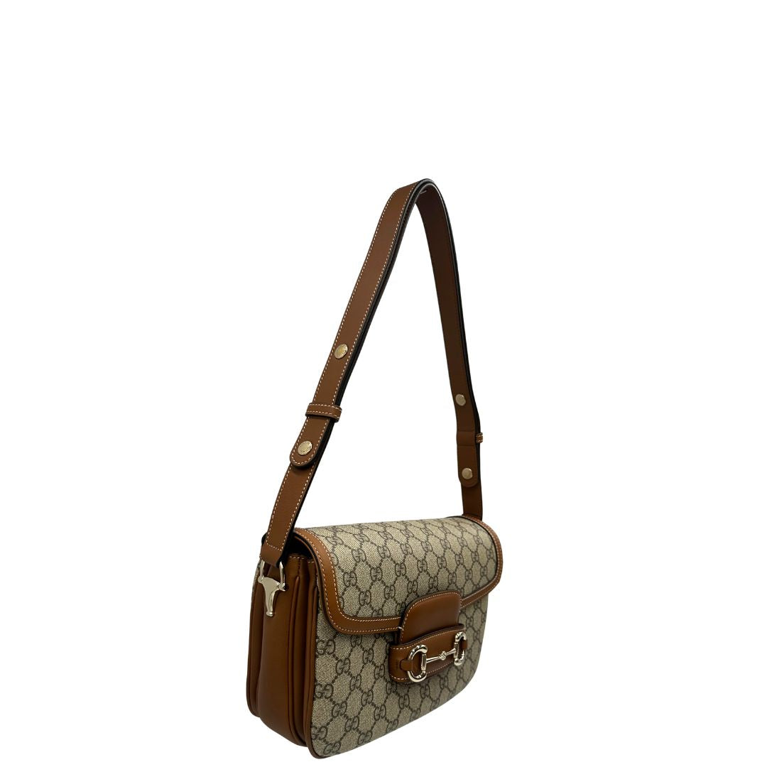 Laterale, Borsa Gucci in canvas beige GG e finiture in pelle color marrone con dettaglio Horsebit sulla chiusura. Borsa a spalla media con pattina frontale. Originale usata, di lusso, in ottime condizioni.