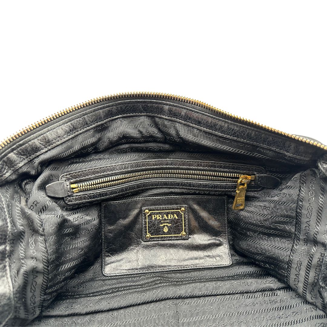 Borsa Prada in pelle nera effetto invecchiato, dotata di doppi manici e tracolla regolabile e amovibile con dettagli in metallo dorato, design capiente e versatile. Originale, usato, di lusso, in ottime condizioni.