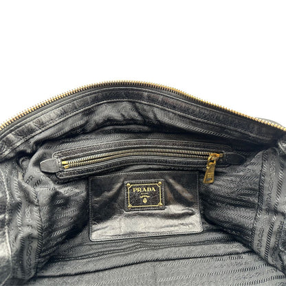 Borsa Prada in pelle nera effetto invecchiato, dotata di doppi manici e tracolla regolabile e amovibile con dettagli in metallo dorato, design capiente e versatile. Originale, usato, di lusso, in ottime condizioni.